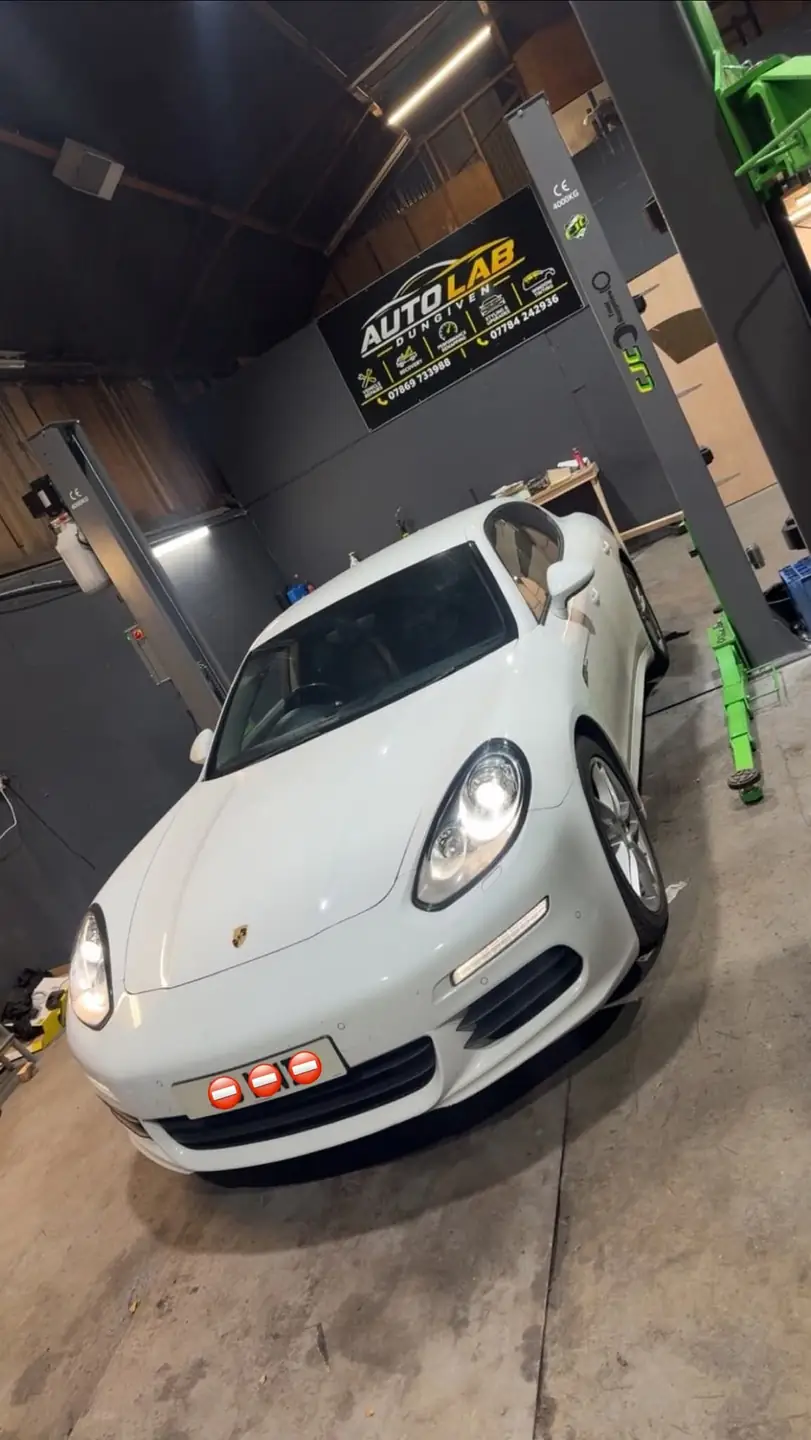 White Porsche Panamera in the Auto Lab workshop, under the Auto Lab Dungiven sign