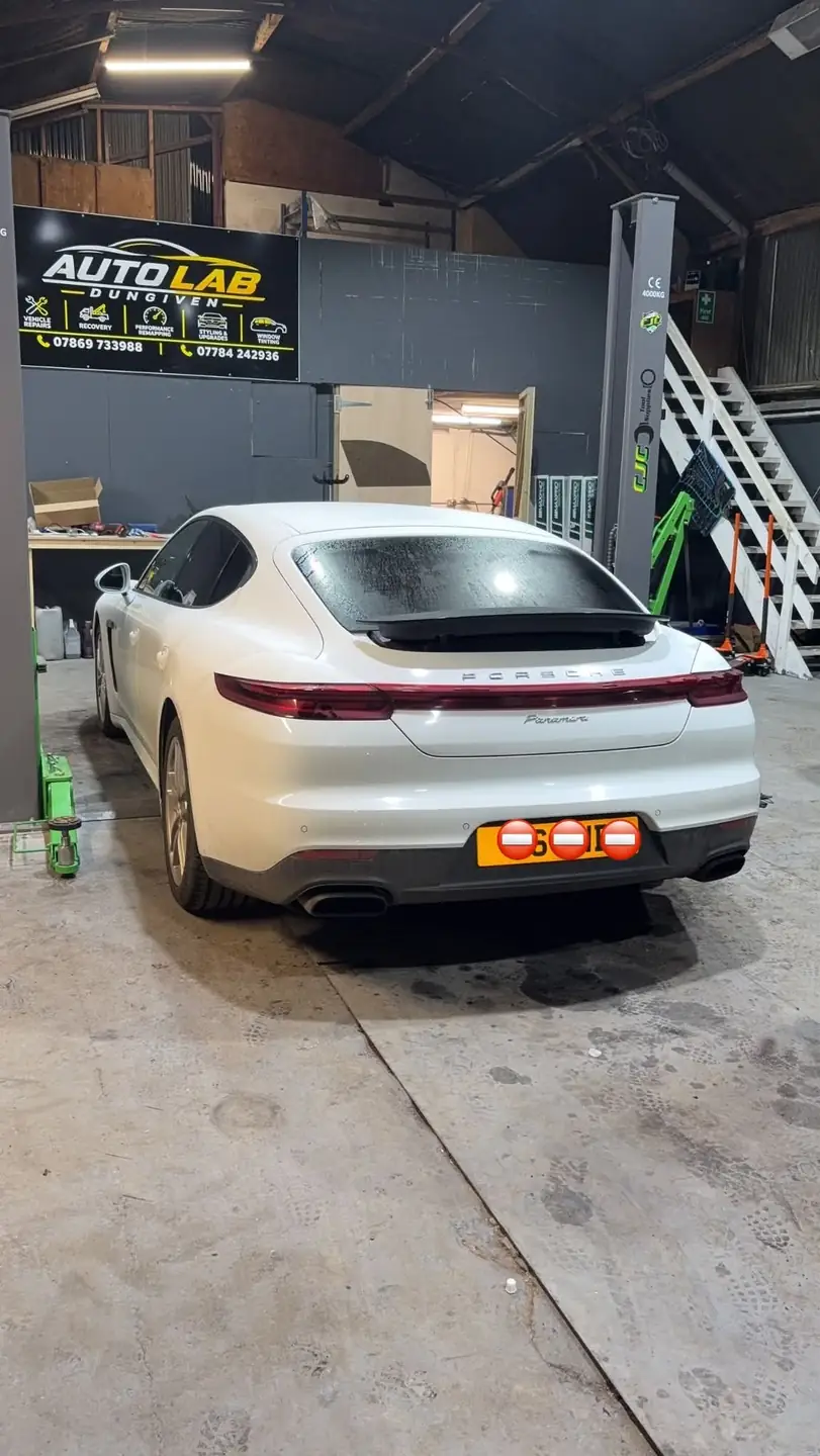 Rear of a white Porsche Panamera in the Auto Lab workshop, under the Auto Lab Dungiven sign